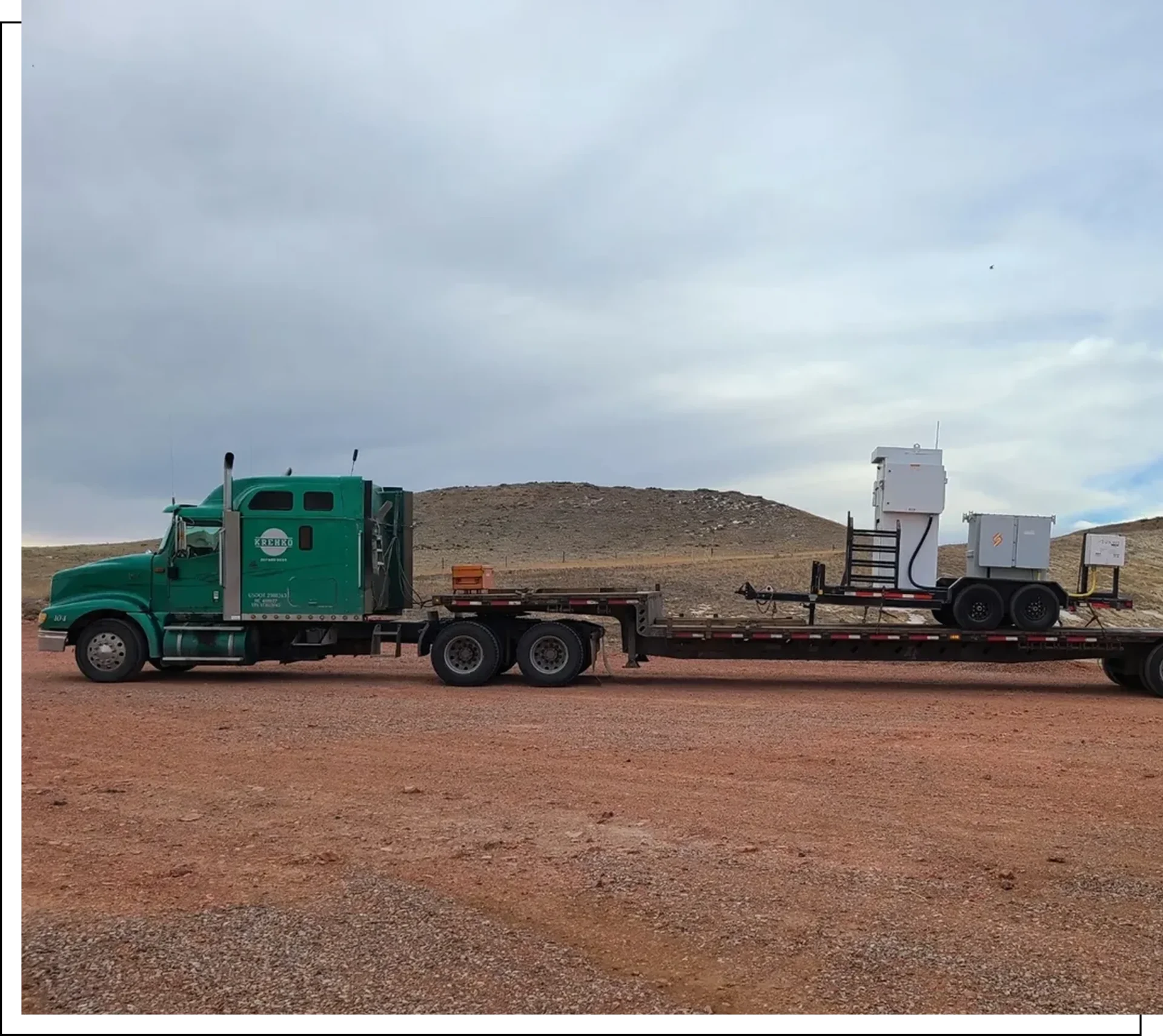 Group 7 Green truck with flatbed trailer in desert.